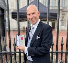 Andrew standing outisde Buckingham Palace holding his award