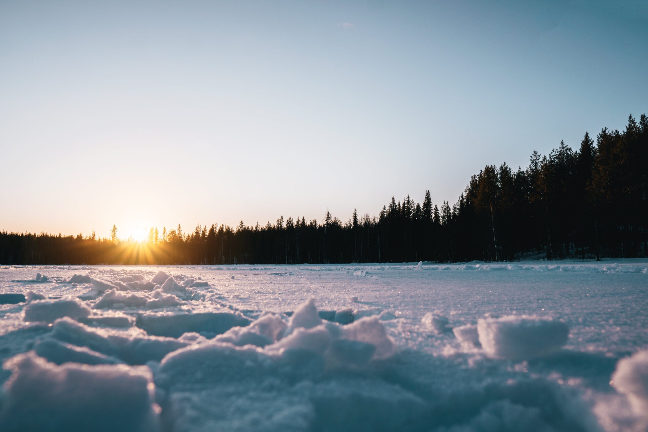 sun setting over frozen lake with snow