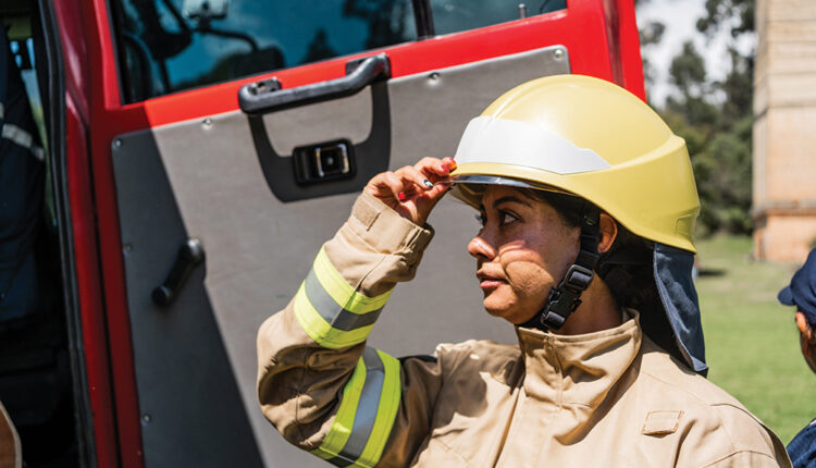 Mid adult firefighter woman getting dressed on fire truck